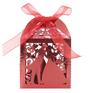 Detail of laser-cut red wedding favor box with bride and groom silhouette and red ribbon