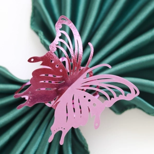 Macro shot of laser-cut pink butterfly napkin ring on elegant dark green satin