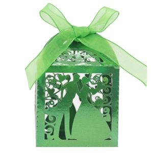 Detail of laser-cut green wedding favor box featuring romantic couple silhouette and ribbon