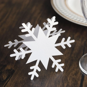 Detailed close-up of hollow white snowflake place card on a wooden table setup