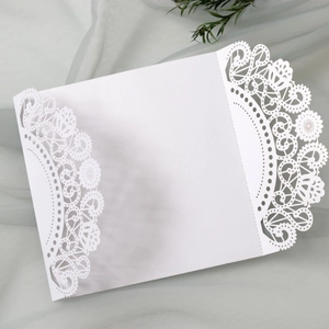 Elegant white laser-cut wedding invitation card with floral lace details on gauze background