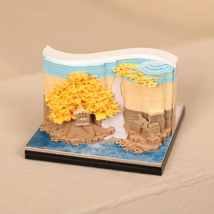 Detailed macro view of 3D paper sculpture memo pad showing golden trees and a waterfall
