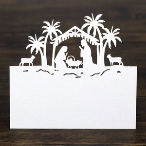 Macro view of white laser-cut nativity scene place card on dark wood background