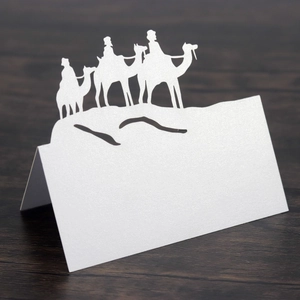 Detailed laser-cut white camel silhouette place card on dark wood table for party