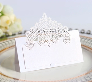 Detailed laser-cut white lace table card placed on elegant dinnerware for wedding setup