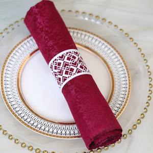 Close-up of white laser-cut geometric napkin ring on a burgundy jacquard napkin