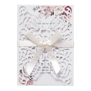 Detail view of laser cut white wedding card with silk bow and floral watercolor accents