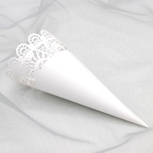 Macro shot of white lace hollow cone for wedding petals on soft light grey tulle