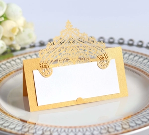 Close-up of laser-cut gold lace place card with white insert on a dinner plate