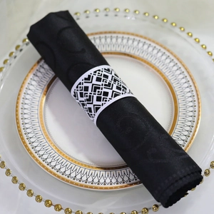 Detail of laser-cut black napkin ring on gold-rimmed plate with satin napkin