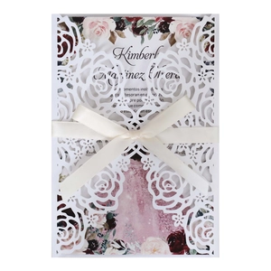 Détail d'invitation de mariage découpée au laser avec ruban crème et motif de rose chic