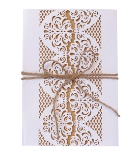 Detailed laser-cut white lace invitation cover with kraft paper insert and hemp rope