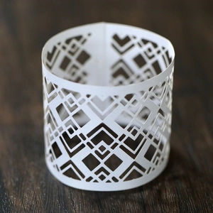 Detail of white laser-cut geometric napkin ring with elegant diamond pattern
