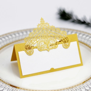 Detail of laser-cut gold lace place card with glitter texture on an elegant dinner plate