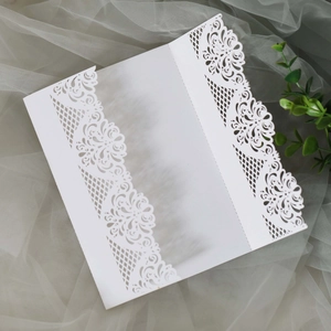 Elegant white laser-cut wedding invitation cover with intricate floral lace patterns
