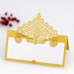 Close-up of golden laser-cut lace table card with a crown design and white writing space