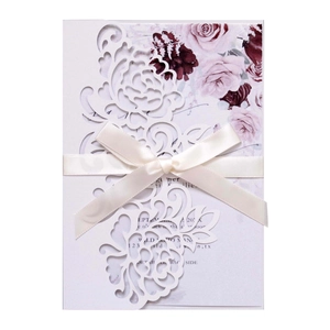 Elegant laser-cut floral wedding invitation with cream ribbon and floral insert card
