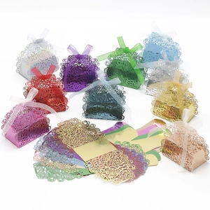 Detailed laser-cut rose patterns on colorful favor boxes with satin ribbon bows