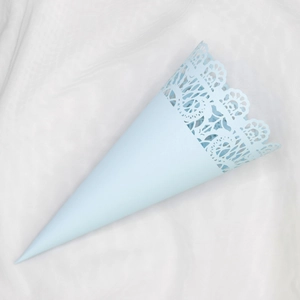 Close-up of light blue paper cone with hollow lace edge on white textured fabric
