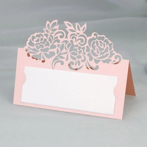Close-up of laser-cut pink pearlescent paper rose place card for weddings and events