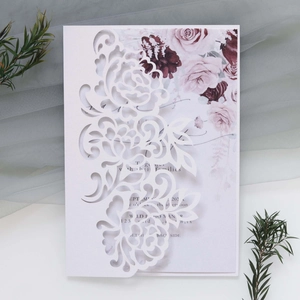 Close-up of white laser-cut rose wedding invitation with elegant floral inner card