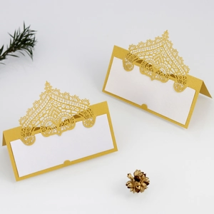 Macro detail of golden laser-cut wedding place card with intricate lace and crown pattern