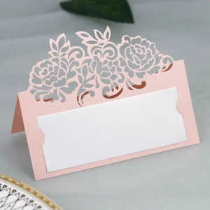 Detail showing pink laser-cut rose patterns on pearlescent cardstock for wedding