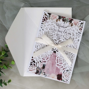 Détail d'invitation de mariage découpée au laser avec insert floral et ruban en soie