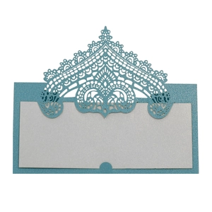 Macro detail of laser-cut lace crown design on light blue glitter wedding place card