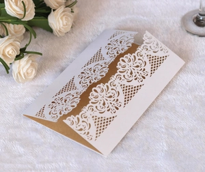 Detail of laser-cut lace floral pattern on white wedding invitation with gold card