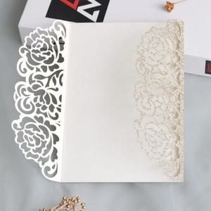 Macro detail of laser-cut rose patterns and golden glitter on ivory invitation card