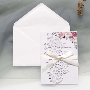 Macro view of laser-cut rose hollow invitation with elegant cream ribbon and floral inner card