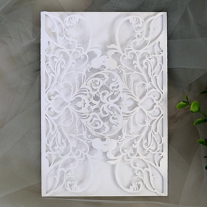 Macro shot of white laser-cut floral invitation card with intricate European patterns