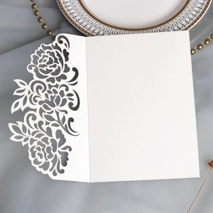 Detailed laser-cut floral pattern on elegant cream wedding invitation with golden decor