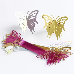 Detail of laser-cut hollow butterfly napkin rings in gold, purple, and silver laser colors