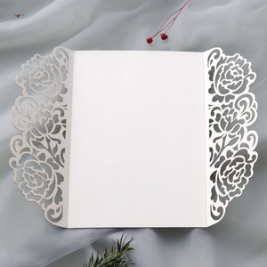 Macro detail of laser-cut ivory rose floral wedding invitation cover with intricate hollow pattern