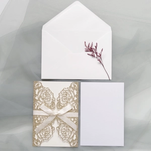 Detail of rose laser-cut wedding invitation with gold glitter and white satin bow