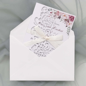 Laser-cut white wedding invitation with pink rose card, cream ribbon, and white envelope