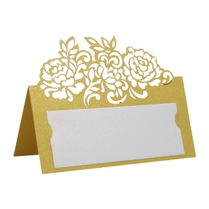 Macro detail of laser-cut gold pearlescent paper table card with floral hollow design