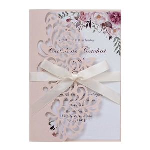 Elegant laser-cut floral wedding invitation with pink cover and white ribbon bow