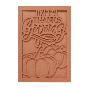 Macro shot of laser-cut Happy Thanksgiving card with pumpkin silhouette in cinnamon paper