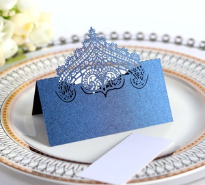 Detail of navy blue laser-cut crown lace place card with glitter texture on a plate