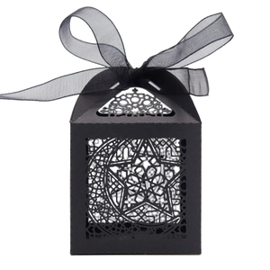 Close-up of black paper candy box with hollow star moon laser cut and organza ribbon bow