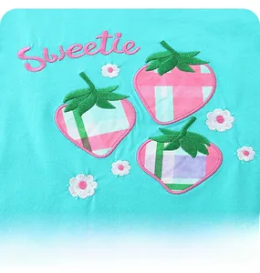 Détail de broderie fraise avec texte Sweetie sur tissu en tricot vert menthe