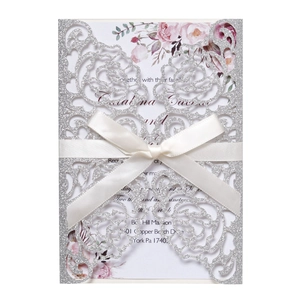 Macro detail of laser-cut rose hollow invitation with glitter finish and silk ribbon bow