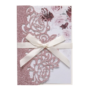 Detail of pink glitter laser-cut wedding invitation with hollow rose and satin bow