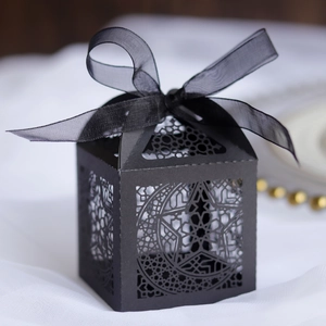 Detail of black laser-cut gift box with star and moon patterns and a black ribbon