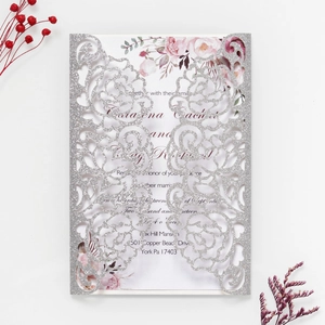 Macro detail of silver glitter rose laser-cut invitation with floral inner card