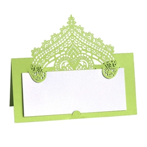 Detail of laser cut green wedding place card with intricate lace hollow pattern and insert