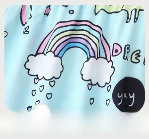 Close-up of light blue cotton fabric featuring colorful rainbow and cartoon cloud prints